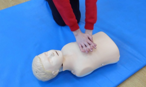 Child practising chest compressions on a teaching aid