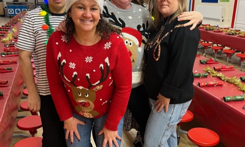 Five school meal supervisory assistants stood in front of the tables set for Christmas lunch